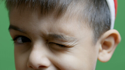 Cute preschool boy winking in slow motion. Close up isolated on green. High quality photo - obrazy, fototapety, plakaty