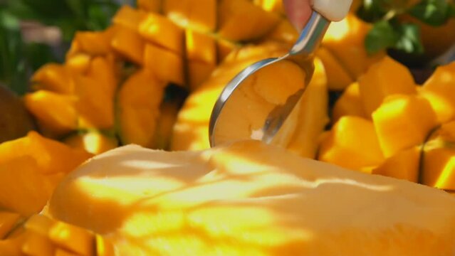 Close-up of the spoon slowly scooping frozen mango ice-cream gelato