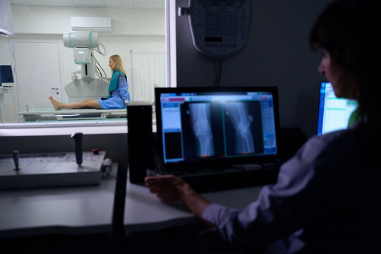 Experienced radiographer is performing digital lower limb radiography on patient