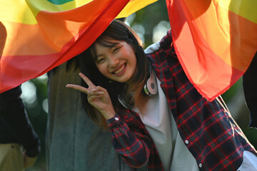 Portrait of Young Activist Girl emerge from Rainbow Flag Campaigning for gender equality and Equal...