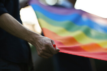 Backlit and close-up photographs of hands spread the rainbow flag, campaign for gender equality and...