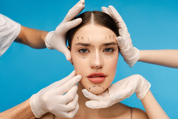 Pretty young woman ready for plastic surgery. Isolated on blue background. Beauty care, anti aging...