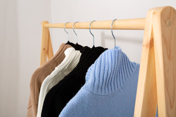 Warm knitted sweaters with a stand-up collar hang on a trempel