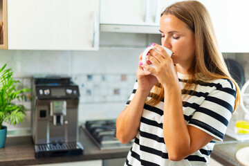 Attractive woman enjoying freshly made coffee in the kitchen in the morning