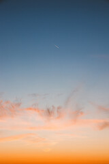Colourful sky during sunset with reddish hues. Blue, orange and golden sky. Airplane flying over in red sun. Abstract sky
