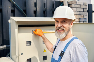 Cheerful electrician turning on power on electric service panel
