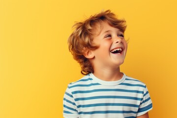 A young boy is seen laughing while holding a toothbrush. This image can be used to promote dental hygiene and oral care
