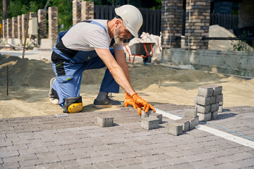 Skilled builder paving road on construction site