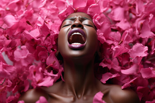 Young African woman having orgasm. Beautiful woman with open mouth and closed eyes enjoying sex lying among rose petals. Sexual experience, getting sexual pleasure, masturbation, cunnilingus.