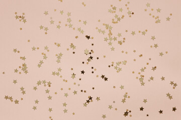 Festive Christmas New Year golden colored star shape glitter confetti on the Peach Fuzz Color of the year 2024 background