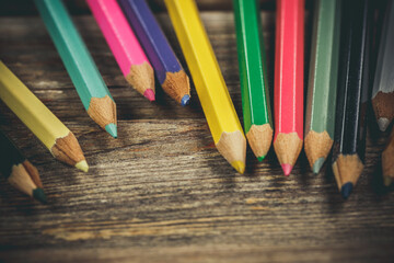 Many colored pencils on a wooden surface, pencils for drawing