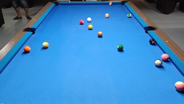 People playing pool billiard on blue table. Pool is a classification of cue sports.