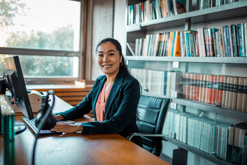 Portrait of a young professional woman sitting at computer desk in library