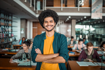 Portrait of a smiling young male student in college library