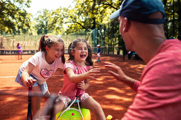 Tennis coach giving tips to little girls during practice