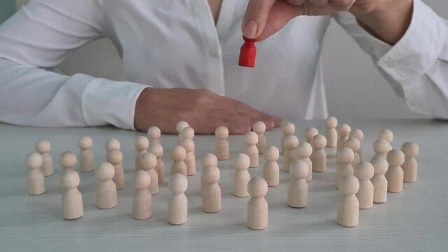 Red wooden figure in row of white identical wooden figures. Selecting a talented employee