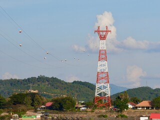 High voltage power lines tower on green mountain, Red high Pylon high-voltage power lines, high voltage electric transmission tower for producing electricity at high voltage electricity poles