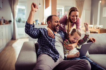 Happy family using tablet on the couch at home - Powered by Adobe