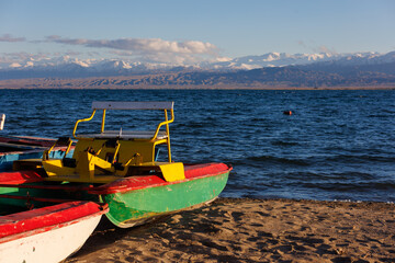 old pedal catamarans on beach of mountain lake at sunny autumnal afternoon.