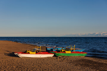 old pedal catamarans on beach of mountain lake at sunny autumnal afternoon.