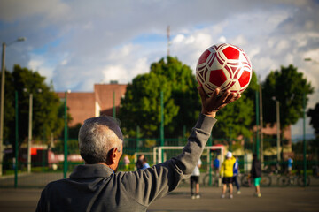 retired older man being a goalkeeper on a soccer field in a park