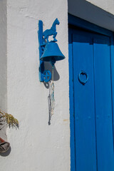 Blue painted iron bell with horse decorating the entrance of a traditional rural house