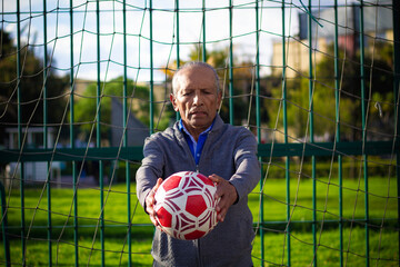 retired older man being a goalkeeper on a soccer field in a park