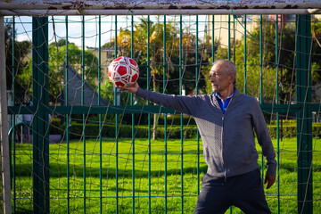 retired older man being a goalkeeper on a soccer field in a park
