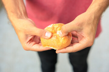 A man's hand holds a round bun, snack and fast food concept. Selective focus on hands with blurred...