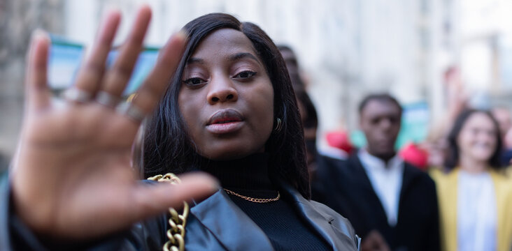 Beautiful female activist leading a protest march with raised hand gesture. Youngsters protesting for protection of civil rights.