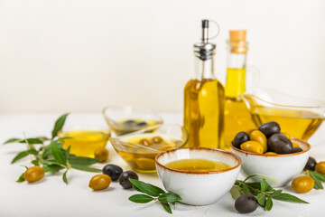 Olive oil in a bottle on a white texture background. Oil bottle with branches and fruits of olives. Place for text. copy space. cooking oil and salad dressing.