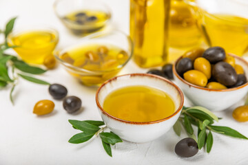 Olive oil in a bottle on a white texture background. Oil bottle with branches and fruits of olives. Place for text. copy space. cooking oil and salad dressing.