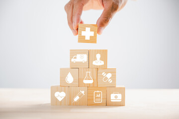 Hand holds wooden block with healthcare and medical icons, signifying safety, health, and family well-being. Illustrating pharmacy, heart care, and happiness concepts. health care concept