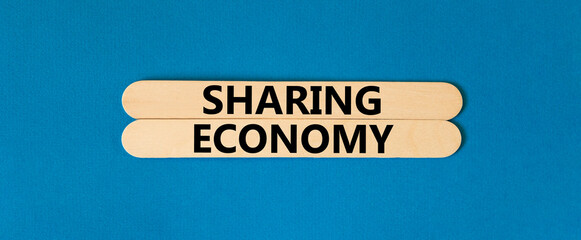 Sharing economy symbol. Concept words Sharing economy on beautiful wooden stick. Beautiful blue table blue background. Business sharing economy concept. Copy space.