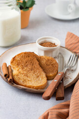 French toast with cinnamon on a ceramic plate, a glass of milk and coffee.