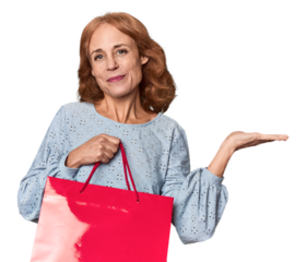 Middle-aged woman with red shopping bag showing a copy space on a palm and holding another hand on waist.