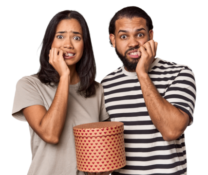 Latina couple with Valentine's heart box biting fingernails, nervous and very anxious.