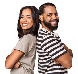 Young Latin couple laughing back-to-back, studio