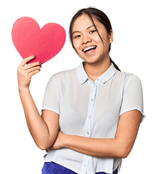 Young Chinese woman holding paper heart, studio setting