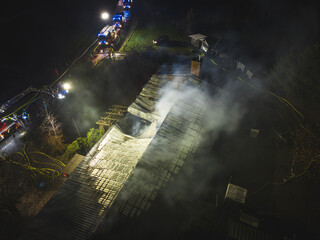 Drohnenaufnahme einers brennenden Gebäudes mit zahlreichen Fahrzeugen der Feuerwehr vor...