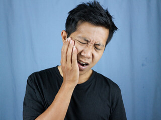 Pain expression of young asian man holding cheek because of toothache. toothache concept