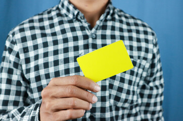 close up attractive business man holding blank yellow mock up card in hand.