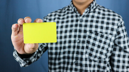 close up attractive business man holding blank yellow mock up card in hand.