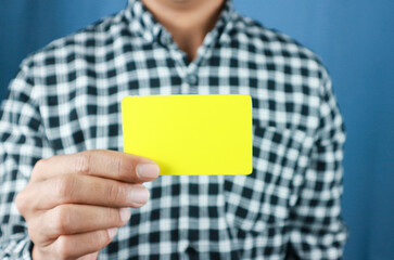 close up attractive business man holding blank yellow mock up card in hand.