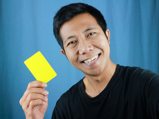 Happy funny face expression Asian man holding empty card on blue background. Transaction concept