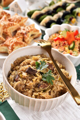 A bowl of sauerkraut with mushrooms and prunes and other dishes for Christmas Eve supper