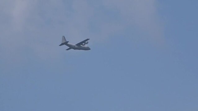 Military Transport aircraft seen flying in the distance through clouds on evacuation air bridge mission