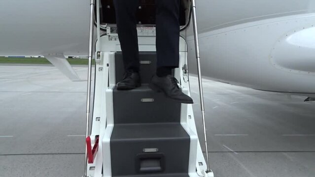 Business man walking door stairs outside private jet shoes