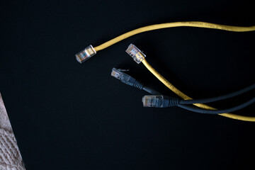 Ethernet cables with gold-plated connectors rest on a dark surface, symbolizing the backbone of...