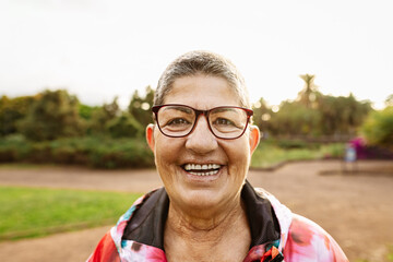 Happy senior woman having fun smiling in front of camera after training activity in a public park